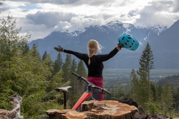 Mountain biker arrives at view point over valley, mountains and forest