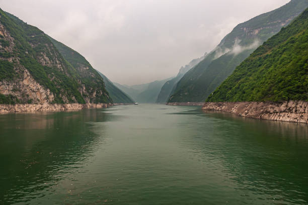 Wushan, Hubei, China - May 7, 2010: Wu Gorge in Yangtze River. Long view over green water into the canyon made by green forested mountains with some cliffs under gray cloudscape.