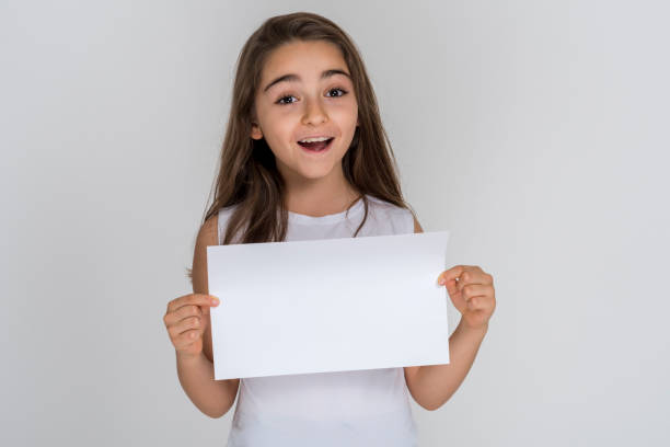 istock Child girl shocked holding white sheet blank isolated 1227628016