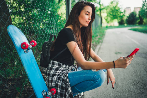 istock Skateboarder girl using her phone 1227629039