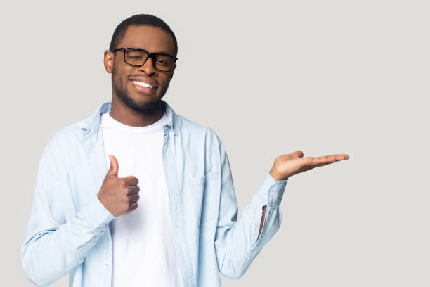 istock Attractive african guy showing open palm and thumbs up gesture 1227633019