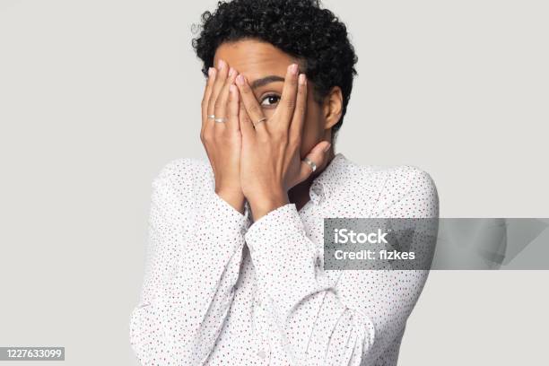 Afraid African Woman Hiding Face With Hands Peeping Through Fingers Stock Photo - Download Image Now