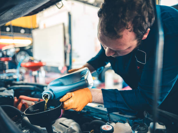 Auto Mechanic working on car Young Caucasian worker at the auto mechanic shop. Location portrait at the place of work. Oil change on the vehicle. lubrication stock pictures, royalty-free photos & images