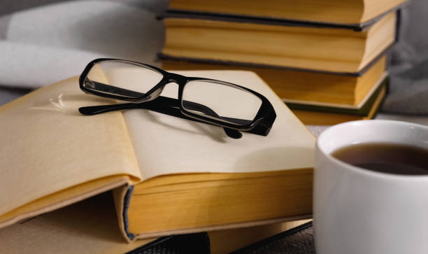 istock Stack of open vintage books with glasses and  cup of tea 1227645588