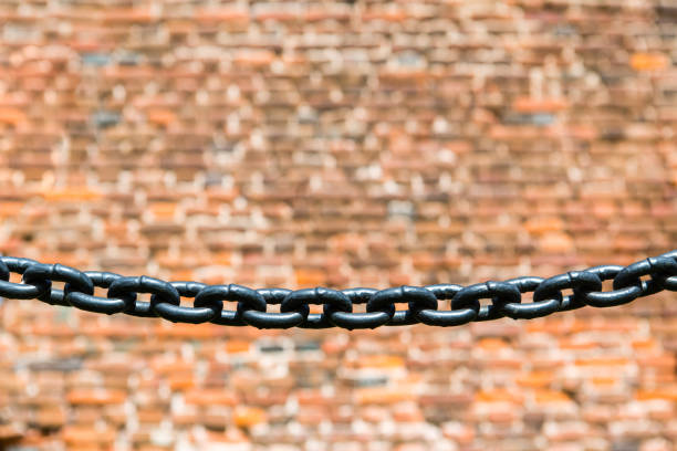 Close up of black iron chain on blurred red brick wall background