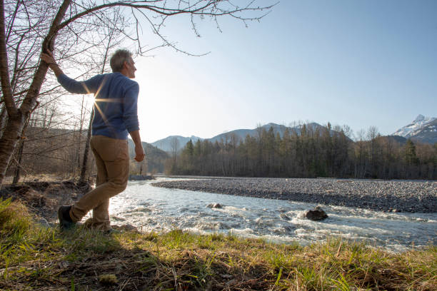 istock Man relaxes by riverbank in the morning 1227647322