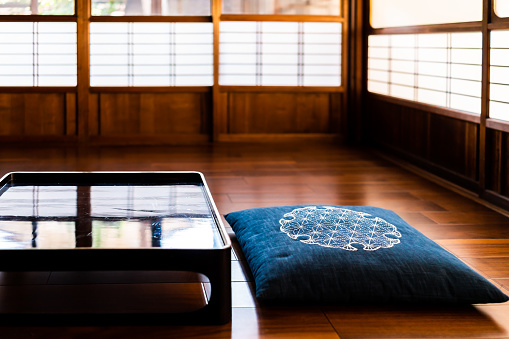 Traditional japanese machiya house or ryokan restaurant with empty black lacquered wood table and nobody with pillow cushion and shoji doors in background