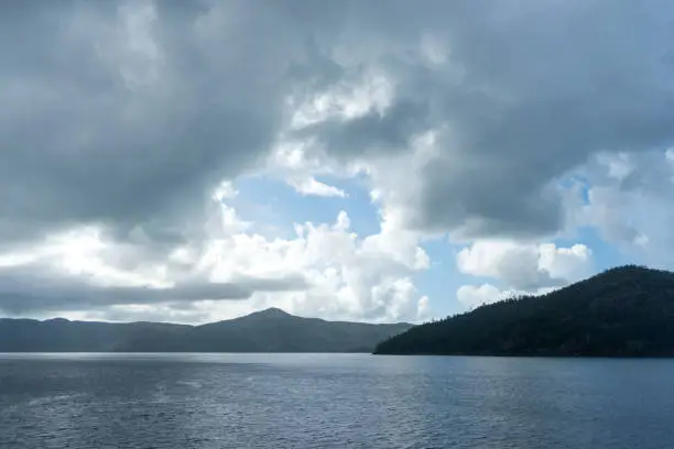 Landscape photo of tropical storm clouds over islands and a dark sea