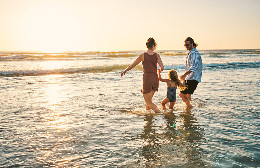 Shot of an adorable little girl spending the day at the beach with her parents