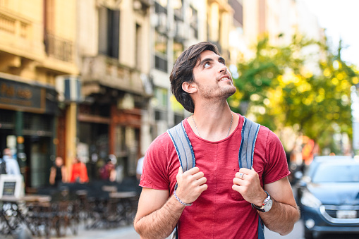 Close-up of young male backpacker exploring side street in downtown Buenos Aires and admiring the sights.