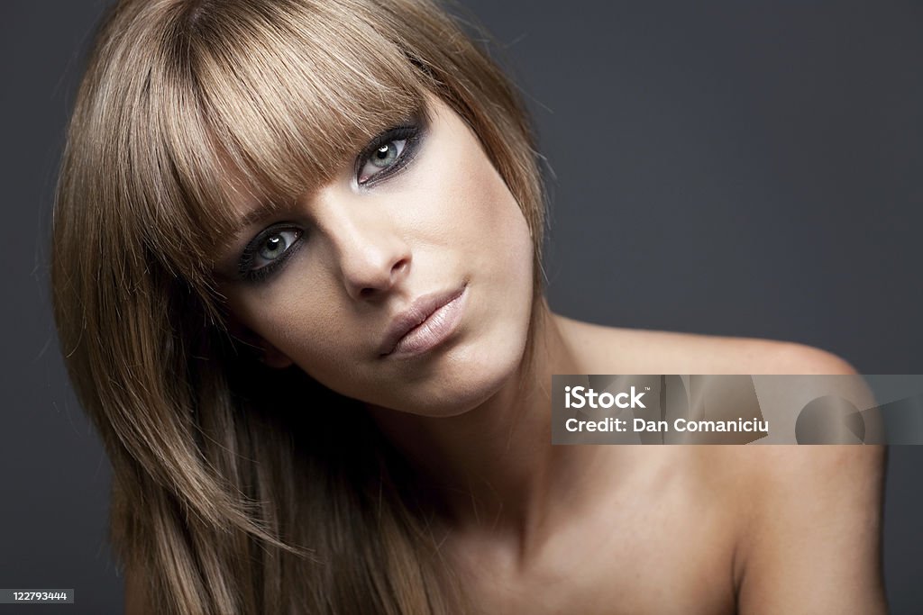 Blond girl with naked shoulders Beauty portrait of a blond woman with naked shoulders on blue background, head tilted on the left side 18-19 Years Stock Photo