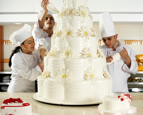 3 chef completing wedding cake.