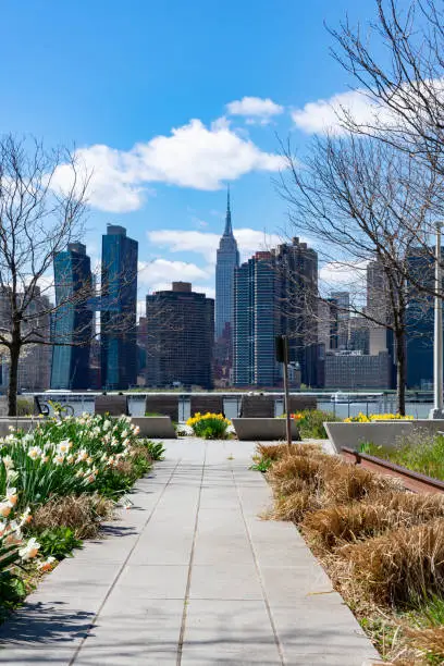 An empty walkway at Gantry Plaza State Park along the East River in Long Island City Queens New York with a view of the Midtown Manhattan skyline during spring