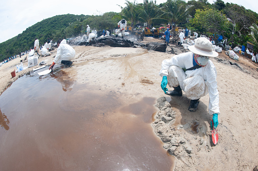 Rayong,Thailand-February 8,2013 : Unidentified Workers and volunteers are shoveling sand with crude oil contaminated on the beach in a large plastic bag on February 8,2013 at Prew beach , Samet island on Khao Laem Ya - Ko Samet National Park in Thailand.