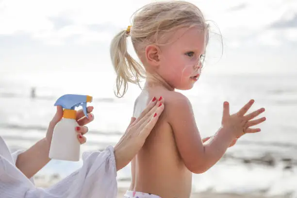 Photo of Mother applying sunscreen protection lotion on cute little toddler girl