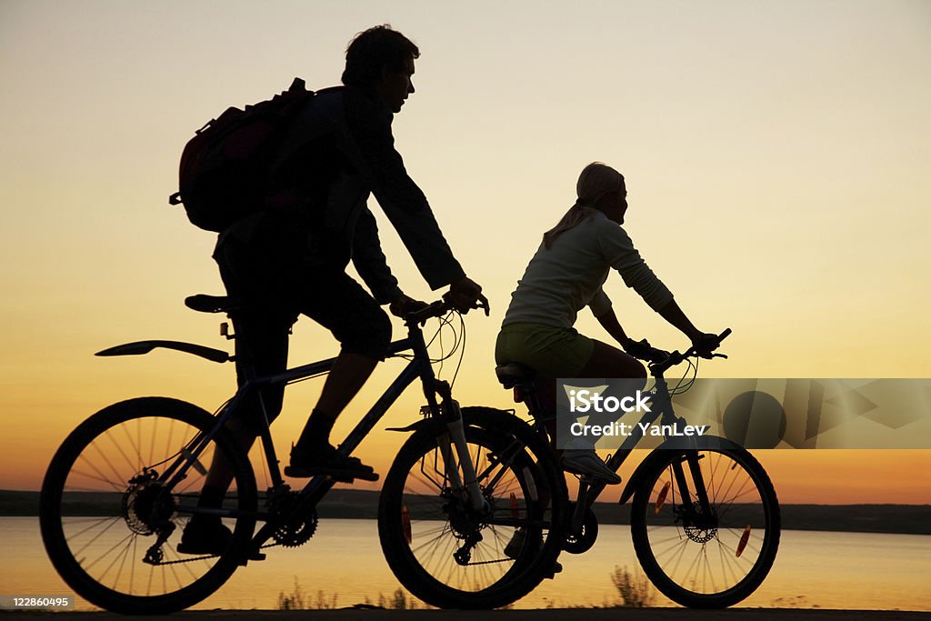 Young couple riding bicycles at sunset.  Beach Stock Photo