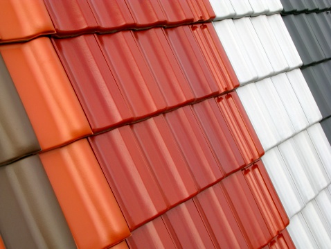 dormer with windows on metal sheet roof with blue sky and sunshine.