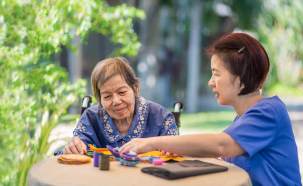 idosa com cuidadora na agulha faz terapia ocupacional para alzheimer ou demência - japanese ethnicity women asian and indian ethnicities smiling - fotografias e filmes do acervo