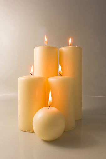 Five Christmas candles, sidelit, against a neutral background.