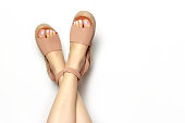 Female legs with white pedicure in summer brown sandals, on a white background, copy of the space