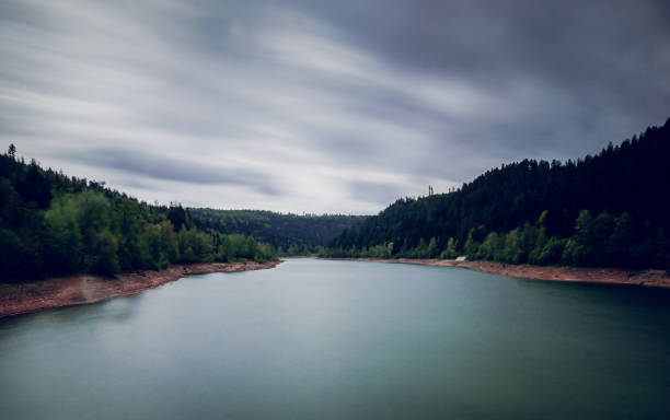 dynamically moving clouds over a reservoir - longtime imagens e fotografias de stock