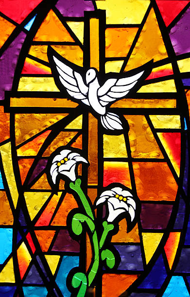 Multicolored Stained Glass Window - Cross with Dove and Lilies Beautiful stained glass panel found in a very old, very small church depicting the dove of peace and containing a cross and lilies.  stained glass photos stock pictures, royalty-free photos & images