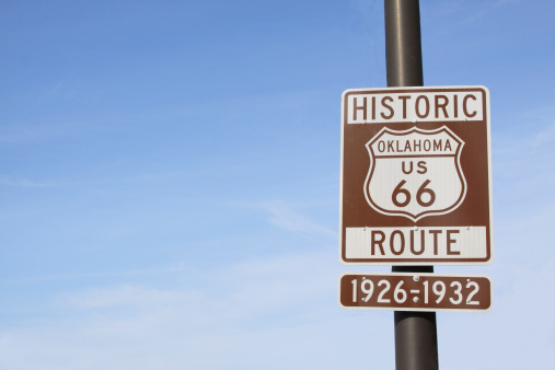 A highway sign is photographed against a blue sky along old Route 66 in Oklahoma. Copy space provided.