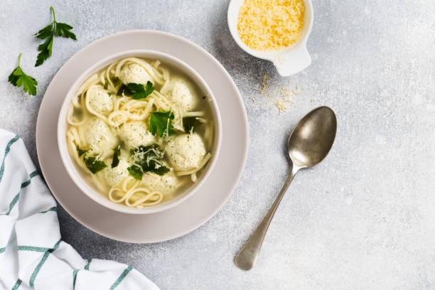 istock Soup with chicken meatballs and egg paste, Parmesan cheese, parsley in a ceramic bowl on a gray table background. Traditional Italian broth.  Top view. 1229528554