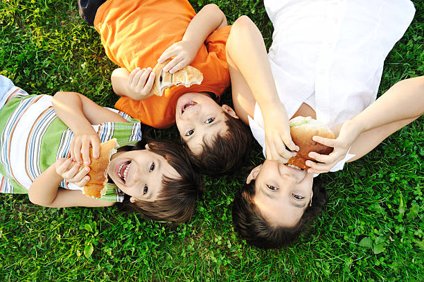 Drei Kinder, die Festlegung auf grünem Gras und Essen sandwiches – Foto