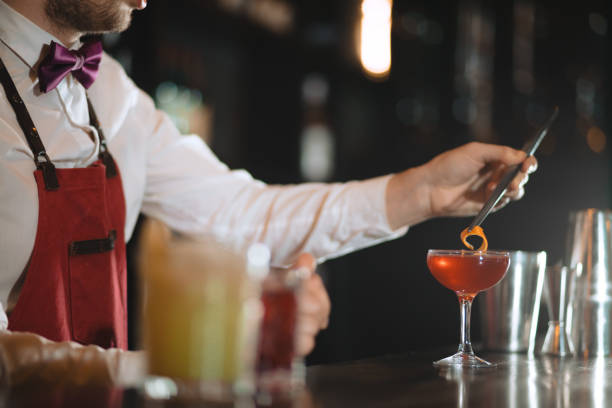 istock Bartender adding to cocktail orange zest with tweezers on the bar counter 1229674526