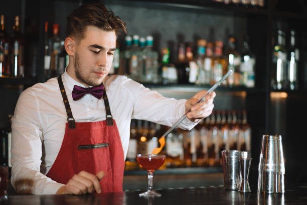 istock Bartender adding to cocktail orange zest with tweezers on the bar counter 1229686941