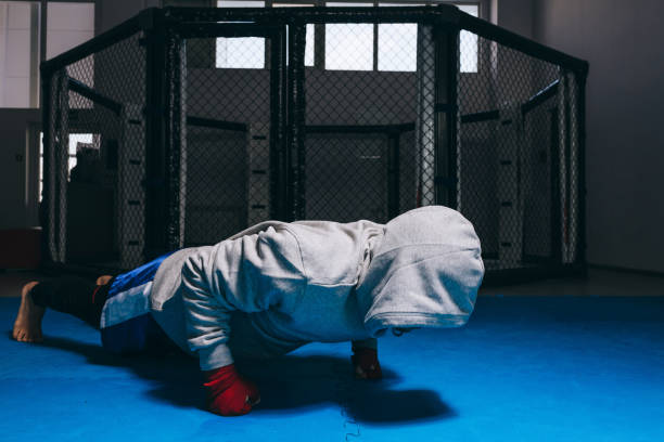 mec méconnaissable dans le sweat à capuche de sport faisant des push-ups sur des poings. - men sweat combative sport boxing photos et images de collection