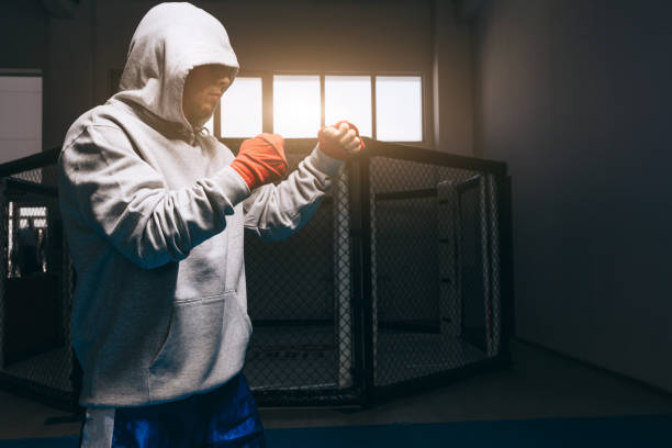 boxeur méconnaissable en sweat à capuche gris avec capuche vers le bas sur ses yeux s’entraîne dans la salle de gym. - karate punching bag caucasian leisure activity photos et images de collection