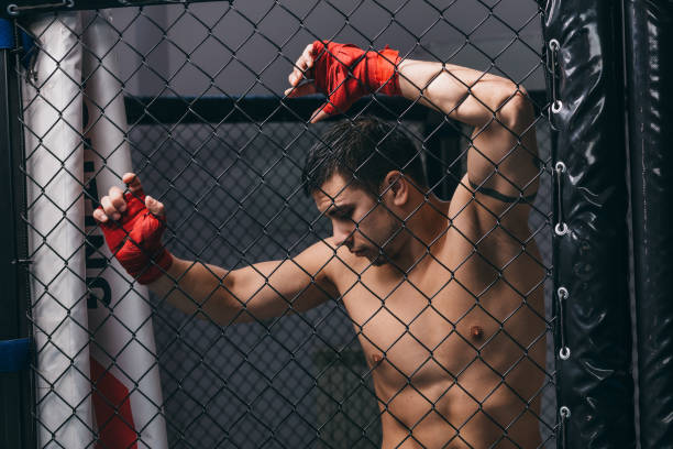 istock Kick boxer with naked torso posing at boxing ring against woven rabitz nettings 1229770868
