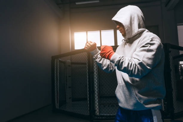 boxeur méconnaissable en sweat à capuche gris avec capuche vers le bas sur ses yeux s’entraîne dans la salle de gym. - karate punching bag caucasian leisure activity photos et images de collection