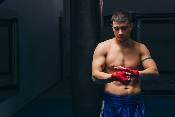 istock Young boxer wrapping his hands with red elastic bandage preparing to workout 1229775425