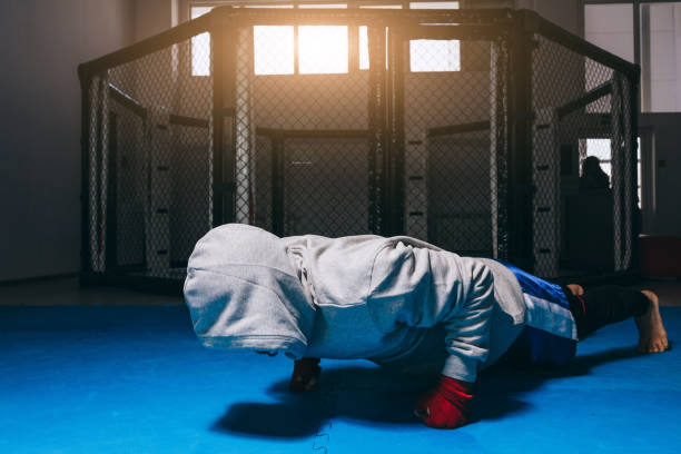 jeune homme faisant push ups dans le centre de boxe, l’échauffement avant l’entraînement. - men sweat combative sport boxing photos et images de collection