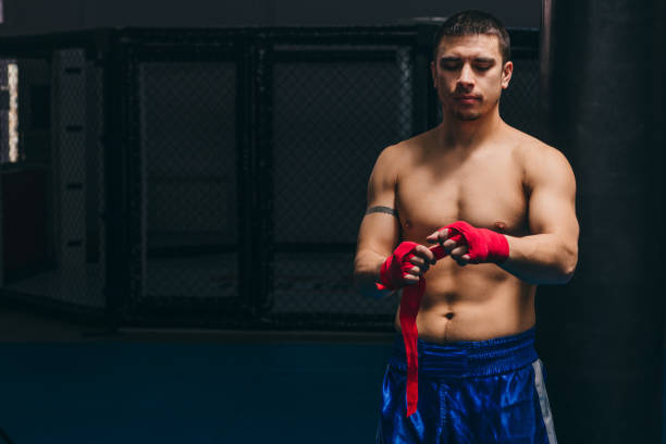 istock Young boxer wrapping his hands with red elastic bandage preparing to workout 1229776442