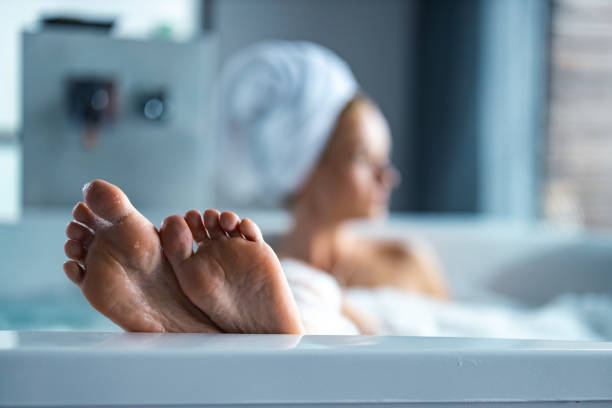 feche acima dos pés da mulher no banho de espuma. - human leg women shower water - fotografias e filmes do acervo