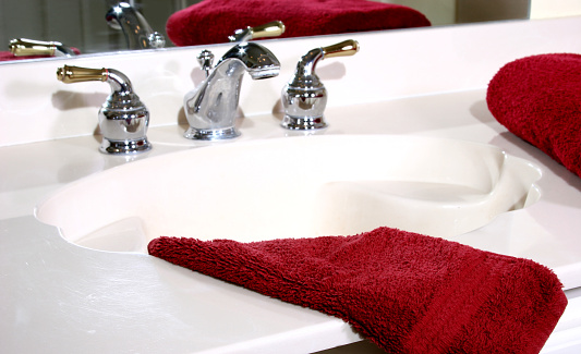 Bathroom sink with red towels and mirror reflection.  