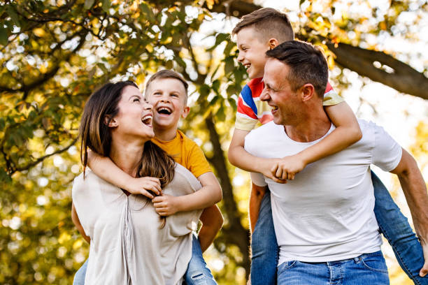 istock Cheerful parents and their sons having fun while piggybacking in springtime at the park. 1229968108