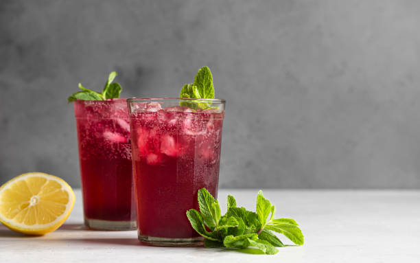 limonada rosa brillante con limón y menta sobre fondo de hormigón gris claro. bebida de refresco de verano. - raspberry soda fotografías e imágenes de stock