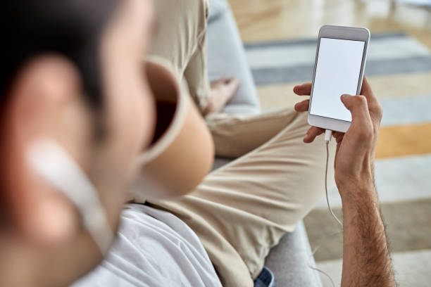 istock Close-up of man using cell phone while drinking coffee at home. 1230004728