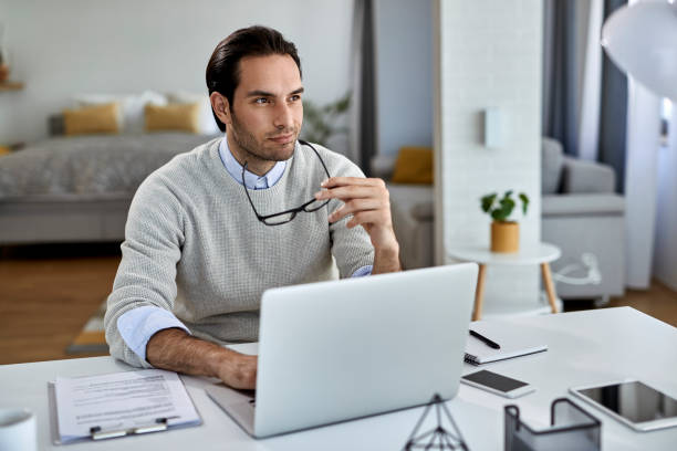 istock Smiling pensive entrepreneur working on laptop at home. 1230019519