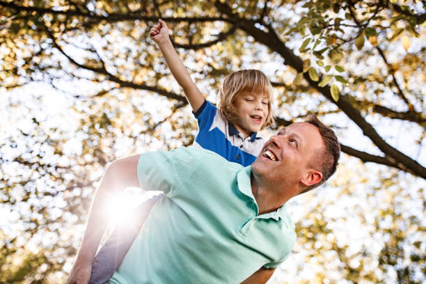 istock Happy father having fun while piggybacking his small boy during spring day in forest. 1230036239