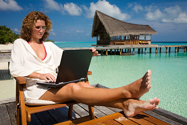 Woman working on laptop by the pool on vacation stock photo