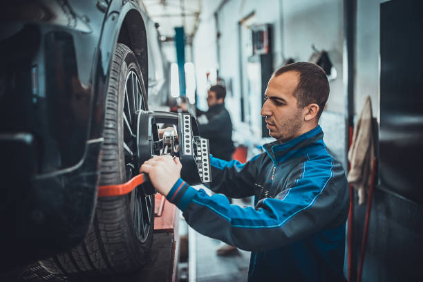 istock Two young auto mehanic sets the wheel alignment equipment on a car wheel 1230104981