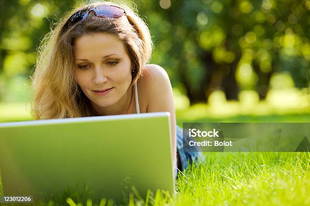 Mujer Joven Usando Una Computadora Portátil En El Parque Foto de stock y más banco de imágenes de Acostado