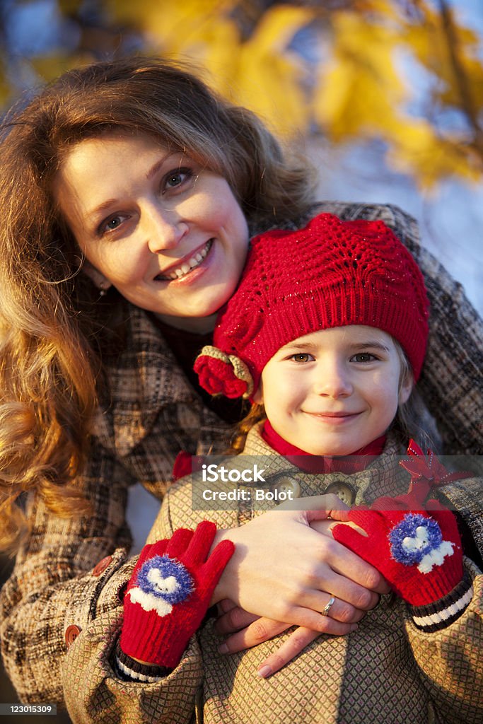 Мать и дочь Бросать сухие листья в Осенний Парк - Стоковые фото 6-7 лет роялти-фри