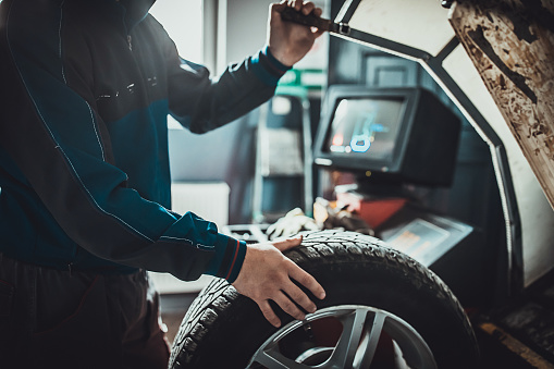 Mecánico balanceando un neumático en el taller de reparación de automóviles photo